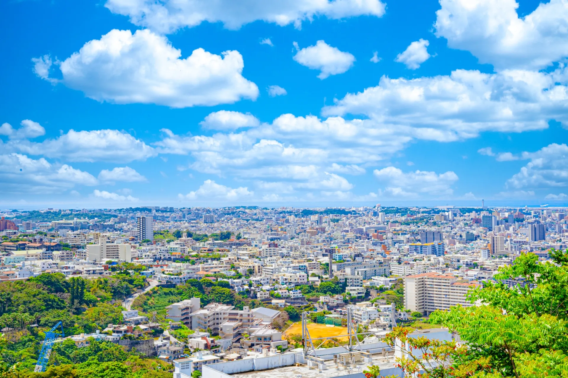 青空の下に白い建物が広がる沖縄の街並み