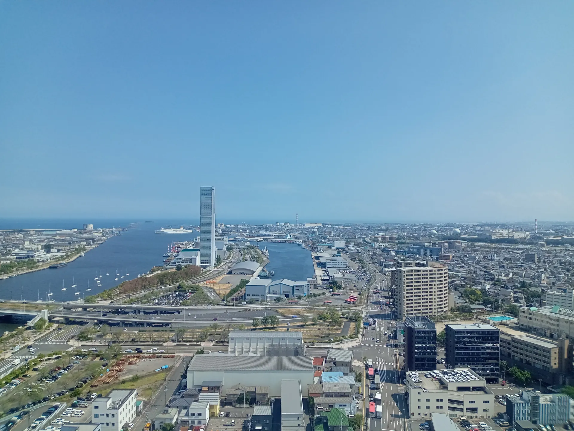 青空の下、川と港に面した新潟の市街地を高い場所から見わたした眺め
